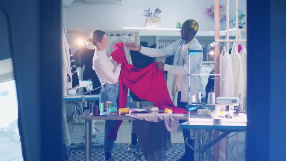 African Tailor and a Seamstress are Wrapping Fabric Around the Dummy alt