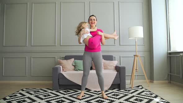 Happy Woman Doing Sit-ups with Daughter in Hands alt