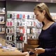 Young Woman Chooses a New Smartphone in an Electronics Store