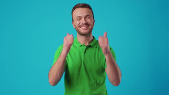 Young Man in Green Tshirt Showing Thumb Up on Blue Background