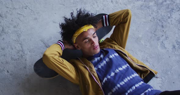 African american man wearing lying on his skateboard in empty parking garage alt