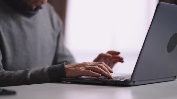 Old Man is Working with Laptop at Home Closeup of Male Hands on Keyboard Retired Person is Surfing alt