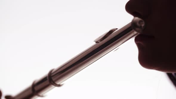 a beautiful girl of caucasian appearance on a white background plays a flute. close-up of the mouth. alt