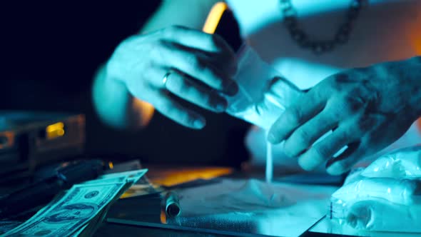 Drugs dealer takes a package with a drug and cuts it with a knife to sample it. alt