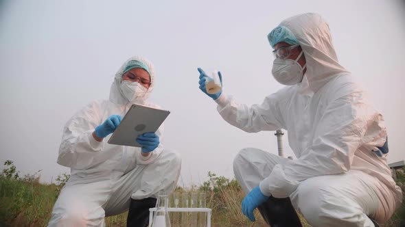 Two Ecologist in protective suits and masks took a sample of water for analysis.