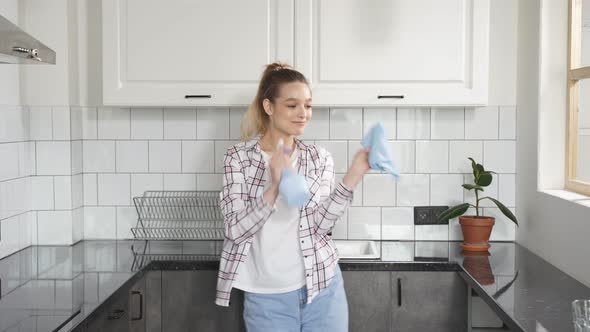 Happy Housekeeper Enjoys the Cleaning Process Dancing in Kitchen with Detergents in Her Hands
