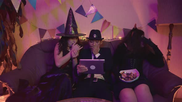 A Group of Friends is Watching a Creepy Halloween Movie on a Tablet alt