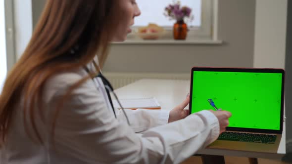 Unrecognizable Blurred Doctor Pointing at Green Screen on Laptop Talking Advertising Web Page Mockup alt