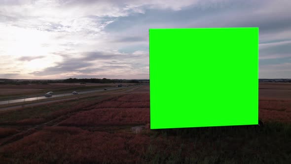 Aerial Drone Footage of Big Billboard with Green Screen near Busy Highway or Motorway at Sunset