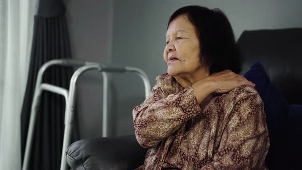 senior woman suffering in shoulder pain in living room
