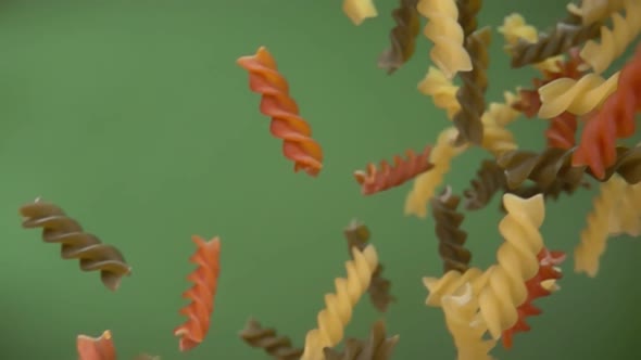 Dry Colored Pasta Fusilli Falling Diagonally on the Olive Green Background alt