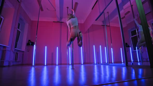 Blonde Slender Woman Dancing Near Pole with Pink and Blue Light at Background alt