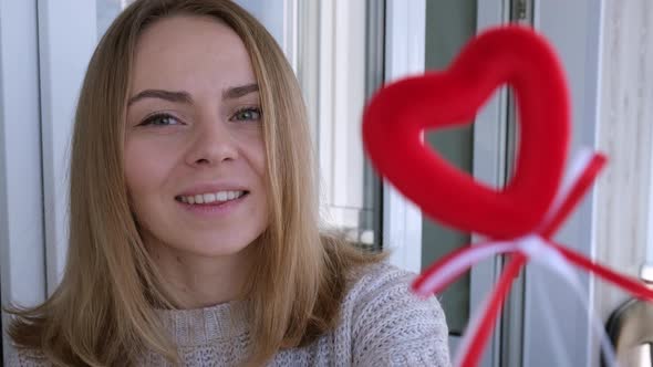 Portrait of Beautiful Blonde Happy Woman Holding Symbol Heart alt