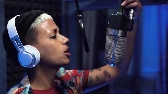 Young professional female singer recording a new song album inside music production studio alt