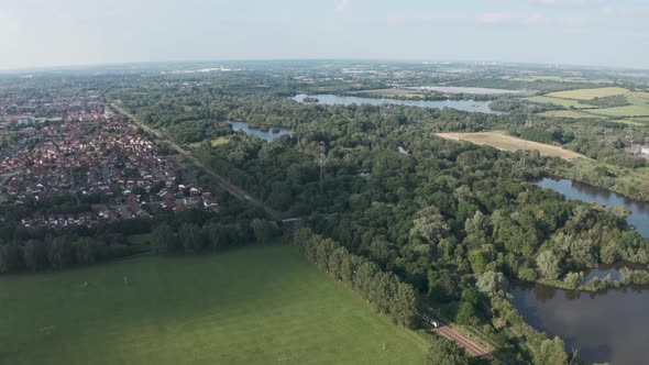 Profile follow drone shot of National rail train passing through British countryside village alt