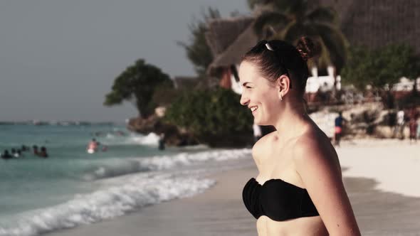 Young Beautiful Woman Stands on Exotic Beach and Looks Into the Distance Sunset alt