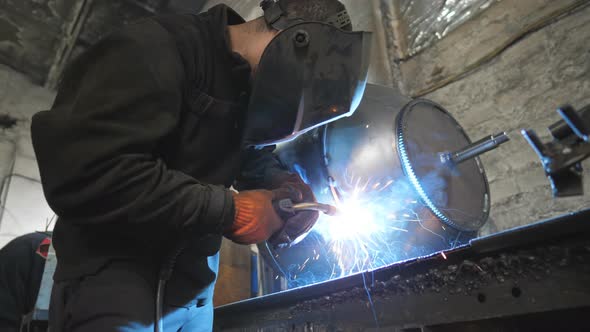 Worker Welding Parts of the Metal Detail Together alt