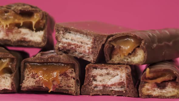 A Lot of Tasty Chocolates on Pink Background. Not Healthy Food. Bitten Sweets Isolated. The Unpacked alt