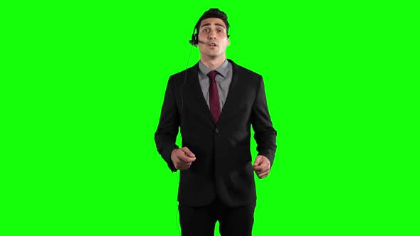 a Caucasian man in suit wearing an earpiece and talking in a green background
