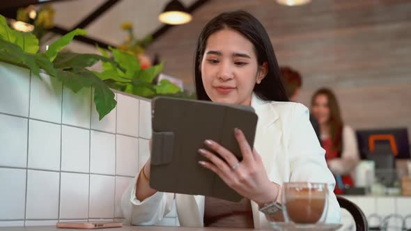 Thoughtful business woman thinking over future business plan at coffee shop, taking notes in tablet alt