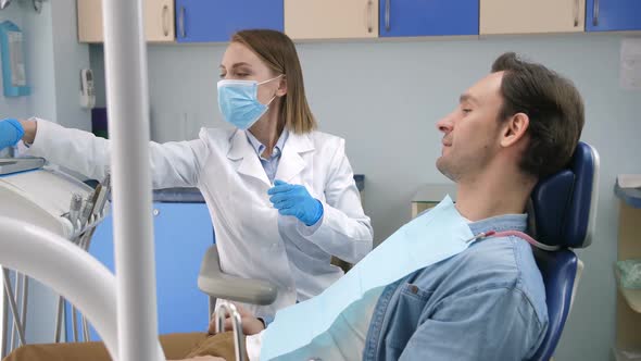 Female Dentist Starting Check-up on Male Client alt