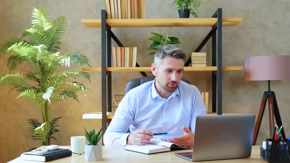Man in home office wears wireless earphones study remote online video conference call with tutor alt