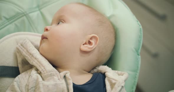 Portrait of the Cutiest Infant Lying in Kid Chair Watching Aside and at Camera alt
