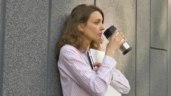 Female Portrait of Young Woman with Silver Laptop and Cup of Coffee Waiting for a Meeting Near Dark alt