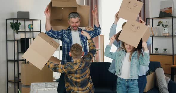Family with Two Kids Dancing in Face Boxes and After Taking them off Hugging Each other in the Room alt