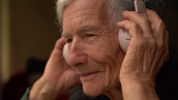 Close Up of Old Lady and Modern Technology Enjoying Music with Eyes Closed alt