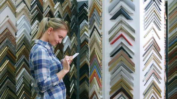 Smiling female customer looking for frame standing near alt