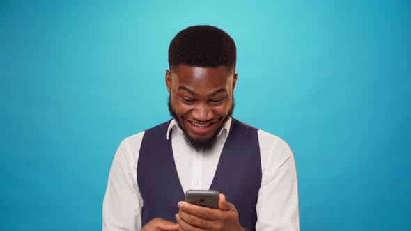 Young African American Man Holding Smartphone Celebrating Victory
