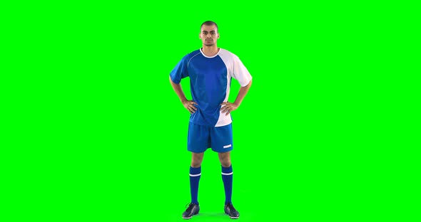 Confident football player standing against green screen alt