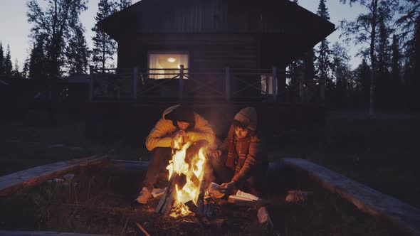 Men sitting near fire in countryside alt