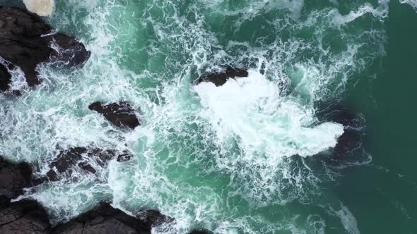 Aerial view of ocean waves splashing in the rocky beach