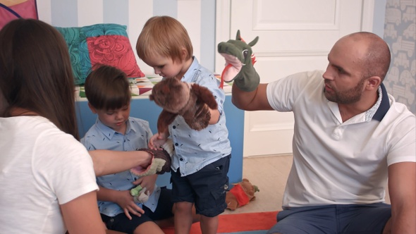 Father and mother playing animal hand puppets with their boys