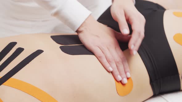 Therapist is applying kinesio tape to female body. Physiotherapy, kinesiology and recovery. alt