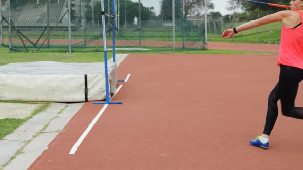 Side view of Caucasian female athlete practicing javelin throw at sports venue 4k alt