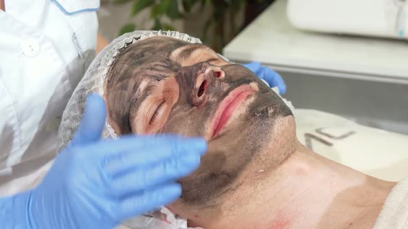 Cosmetologist Preparing Face of Male Client for Carbon Facial Peeling alt