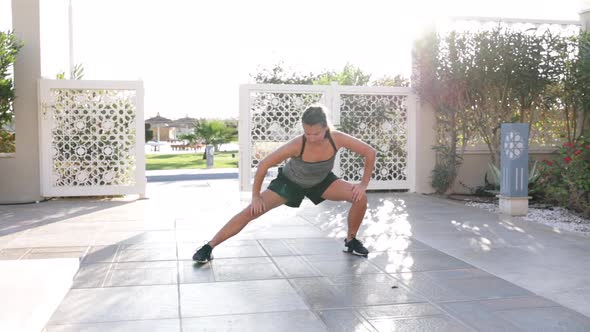 Young woman doing stretching exercise outdoors on a sunny morning