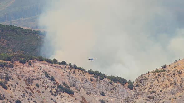 Helicopter flying in front of smoke from forest fire in Utah alt