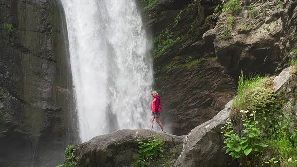 Hiking Woman in Red Jacket Walking Near Big Waterfall