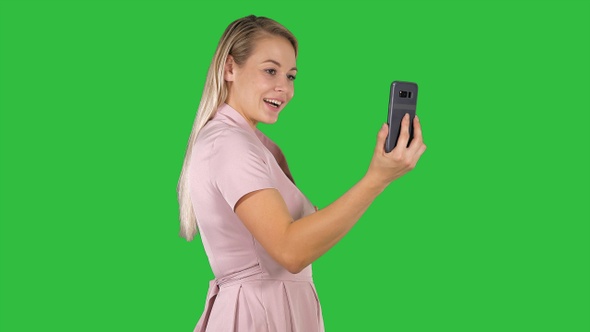 Female in pink dress making video call with her smart phone alt
