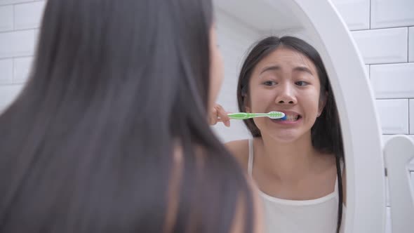 Daily routine concept. Asian woman brushing teeth in the bathroom. 4k Resolution. alt