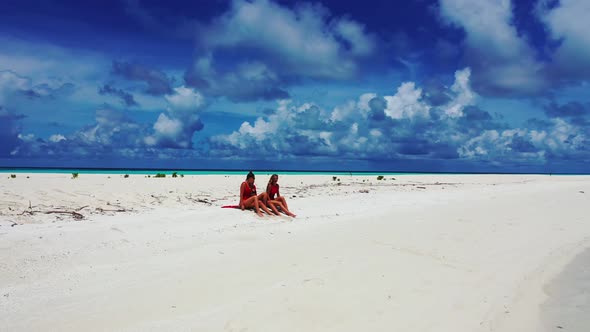 Sexy smiling ladies on vacation spending quality time at the beach on sunny blue and white sand 4K b alt