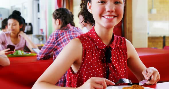 Portrait of happy schoolgirl having breakfast alt