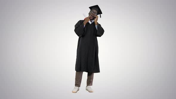 Smiling African American Male Student in Graduation Robe Talking on the Phone Sharing Happy News on alt