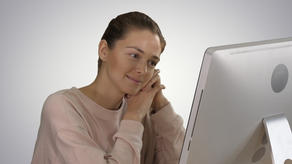 Blonde Girl with Pink Pullover Looking at Monitor of Computer alt