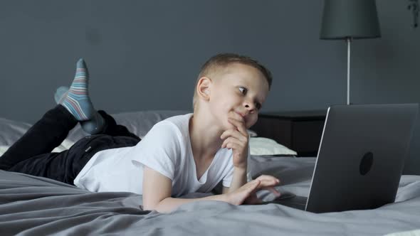 A Small Child Uses A Computer, Looks at The Laptop Screen, Watches Videos or Cartoons alt