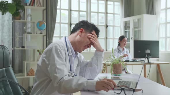 Asian Man Doctor Is Using Laptop Computer And Headache In Workplace. Medical Concept alt